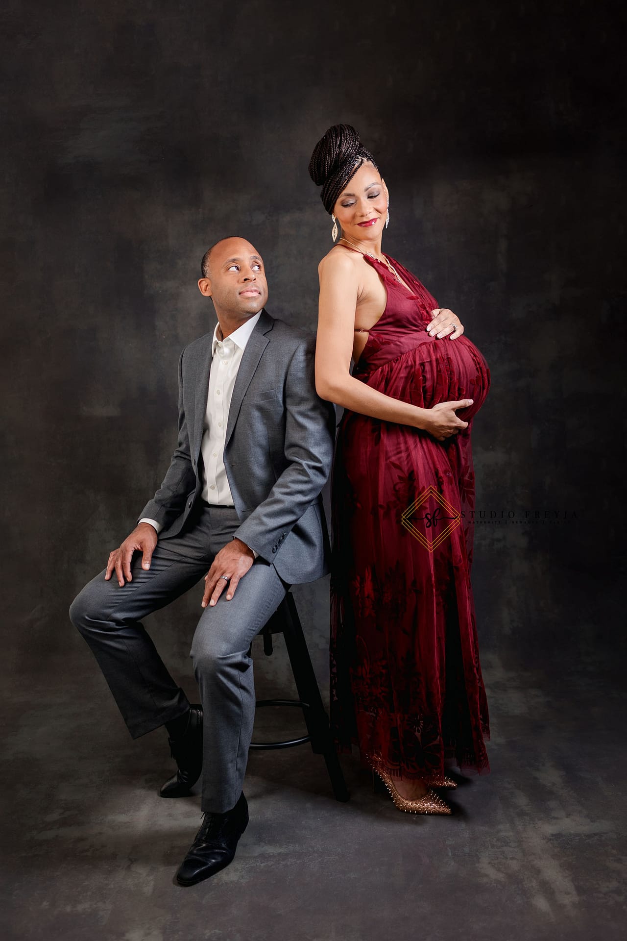 Mom and dad looking at each other during maternity photos in studio