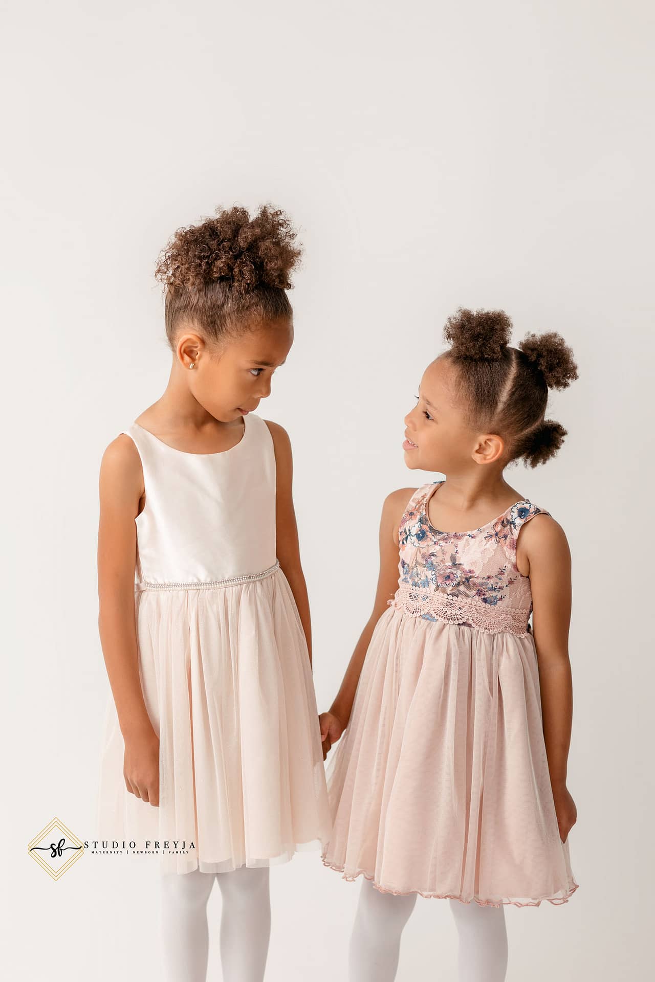 Cute sibling image of sisters looking at each other during maternity session