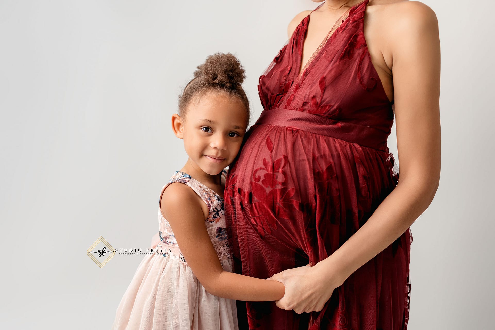 Up close image of bump and sister during studio maternity session in San Diego