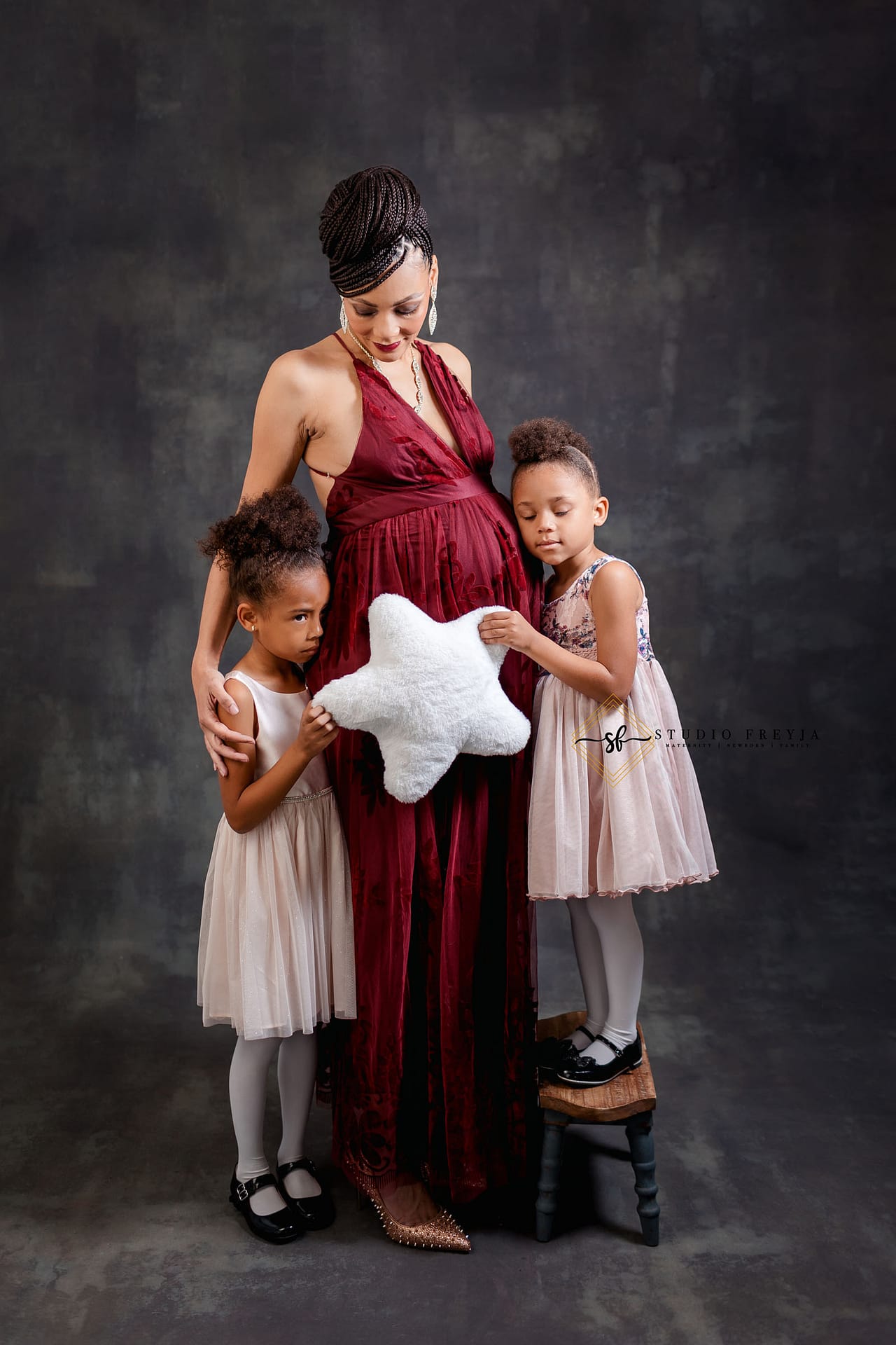 Mom and her daughters hugging a star during maternity session in San Diego Photography Studio