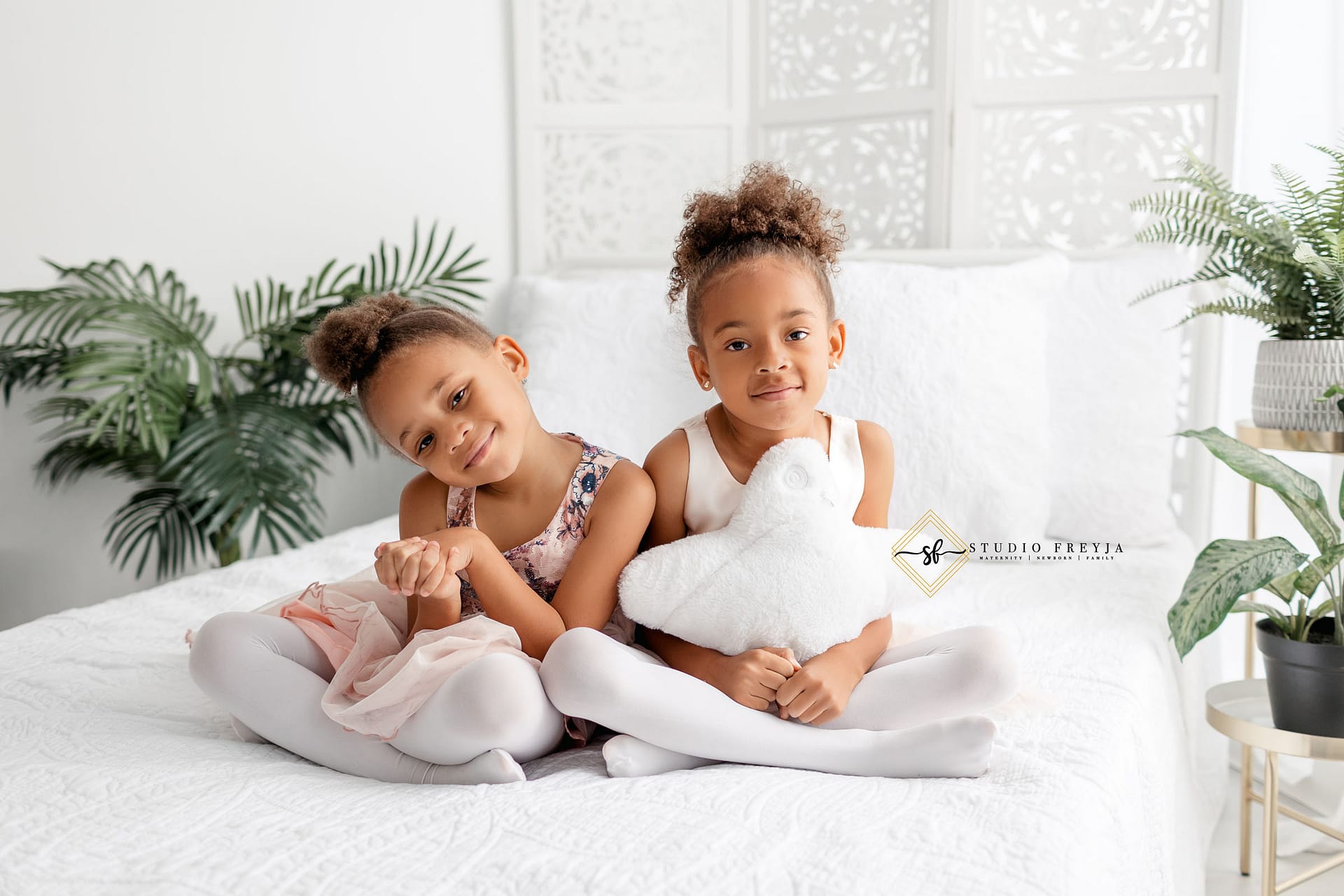 Sisters sitting on a bed with a star pillow during San Diego Maternity Photos